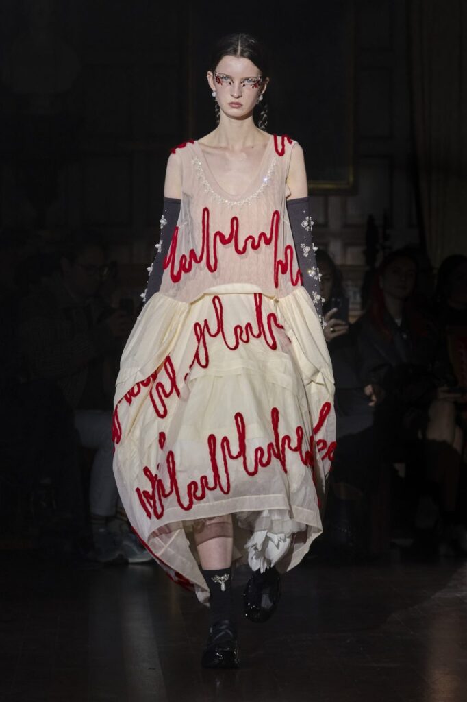 Model wearing balloon style dress with red draping and embellishments at Simone Rocha's AW22 London Fashion Week Show 