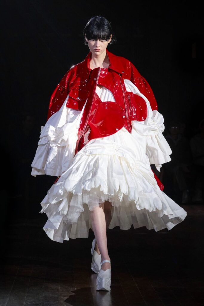Model wearing white dress with red jacket at Simone Rocha AW22 Show.