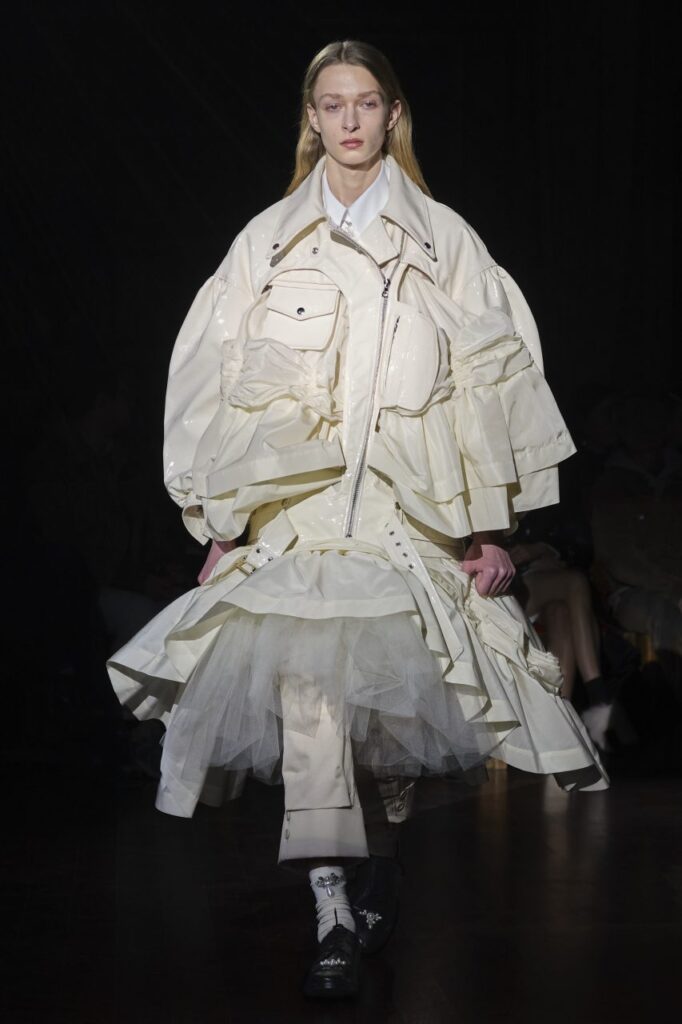 Model wearing oversized white jacket and big petticoated skirt at Simone Rocha's AW22 London Fashion Week Show.