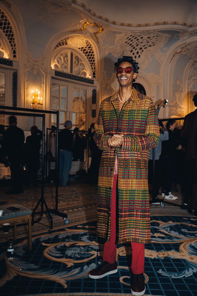 Model wearing long jacket with kente cloth hues, backstage at Ozwald Boateng AW22 London Fashion Week Show. 
