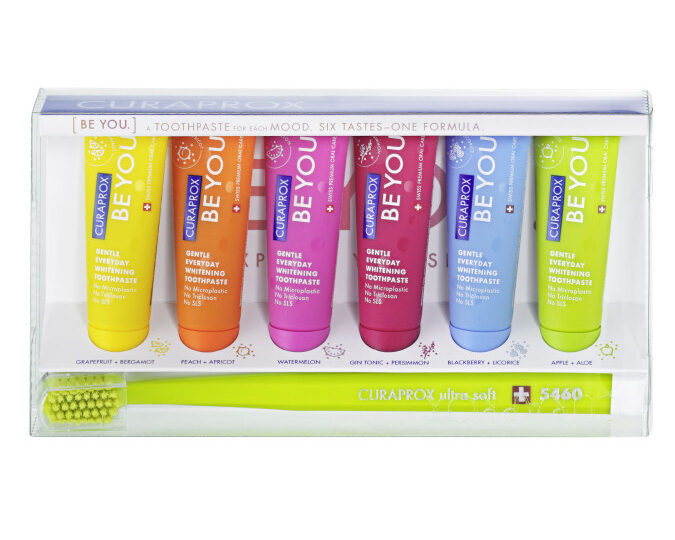 6 colourful toothpastes and a green toothbrush 