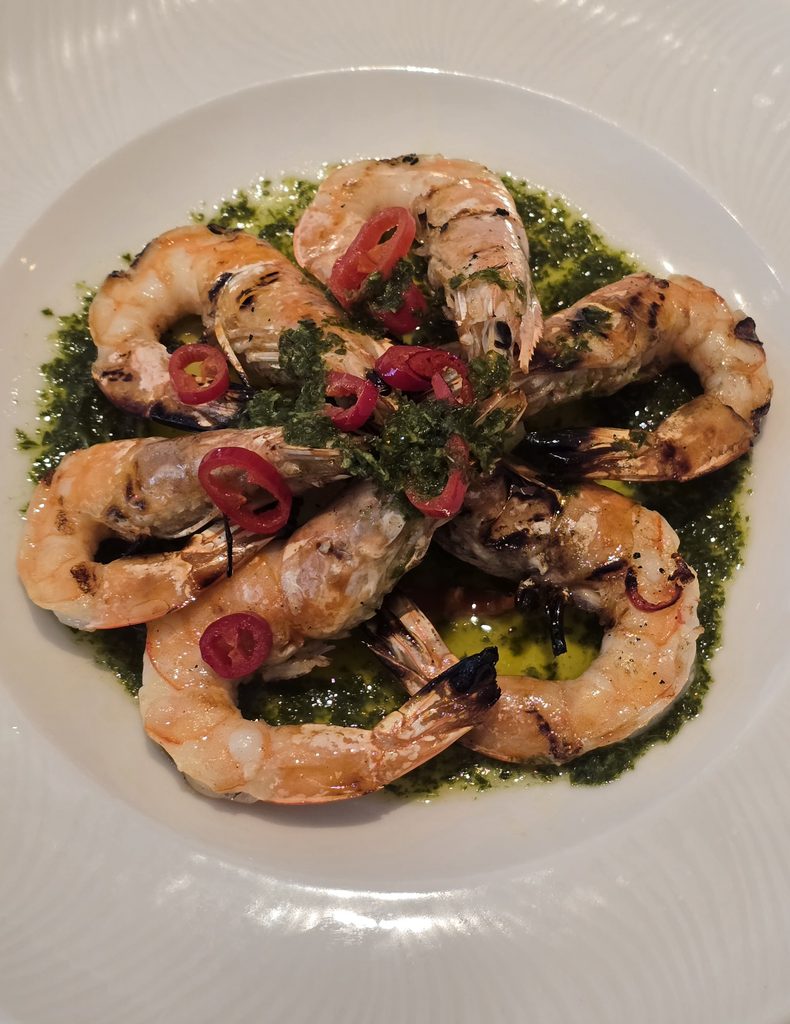Grilled King Prawns with salsa verde, slices of red chilli and lemon.