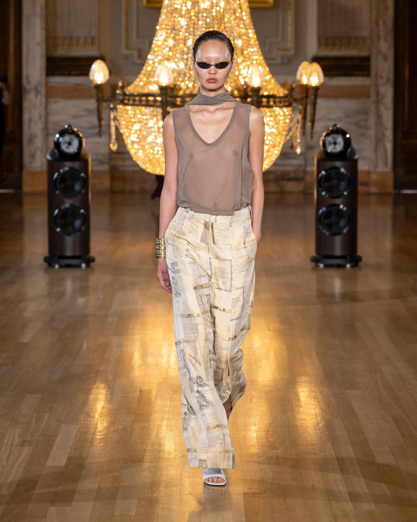 Asian female model with sunglasses, dark beige see-through blouse, ivory & brown patterned pants, and open-toes sandals at Labrum SS27 Runway